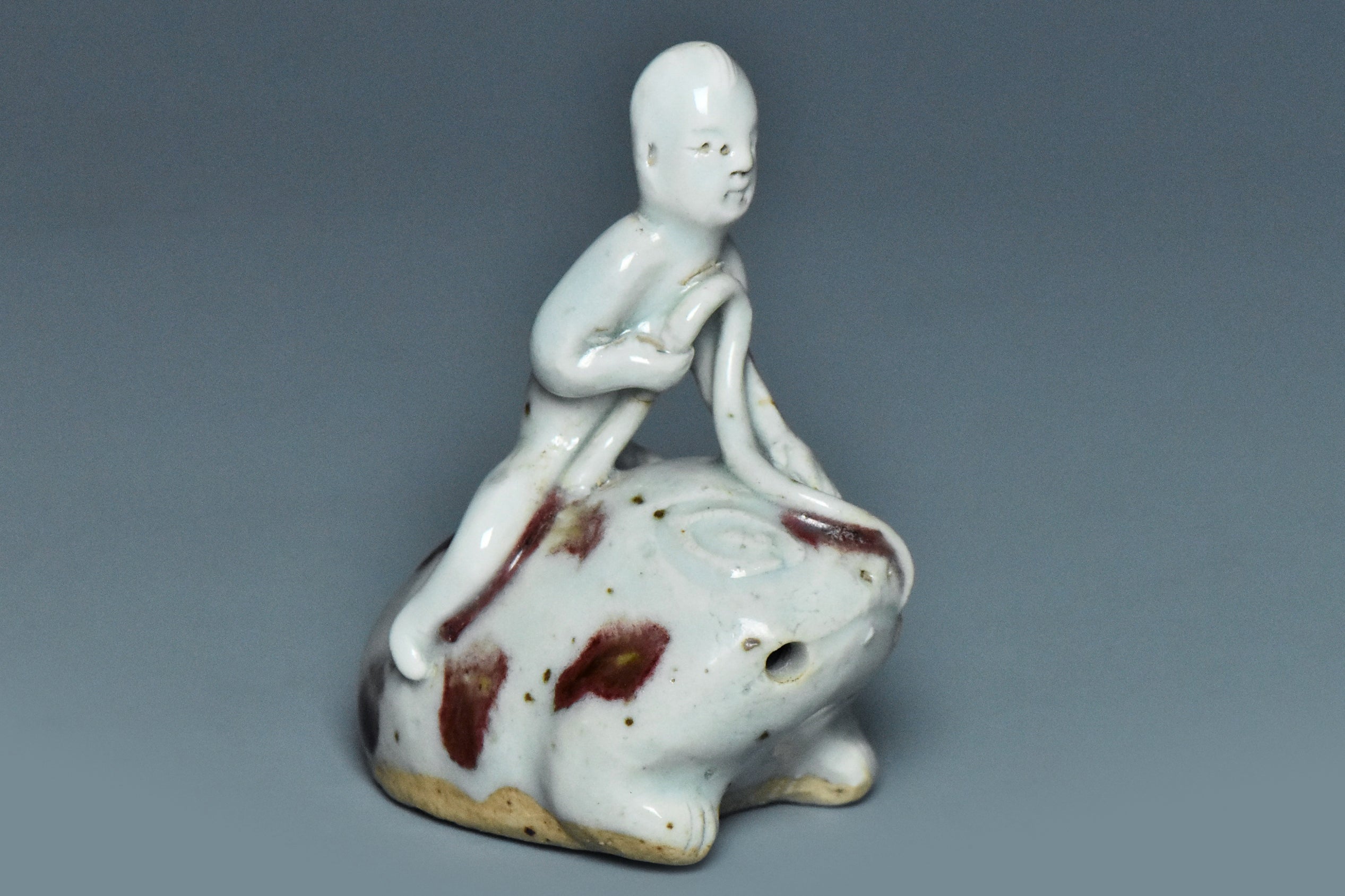 R346: A YUAN DYNASTY STYLE COPPER RED DECORATED FIGURE OF A BOY ON A FROG